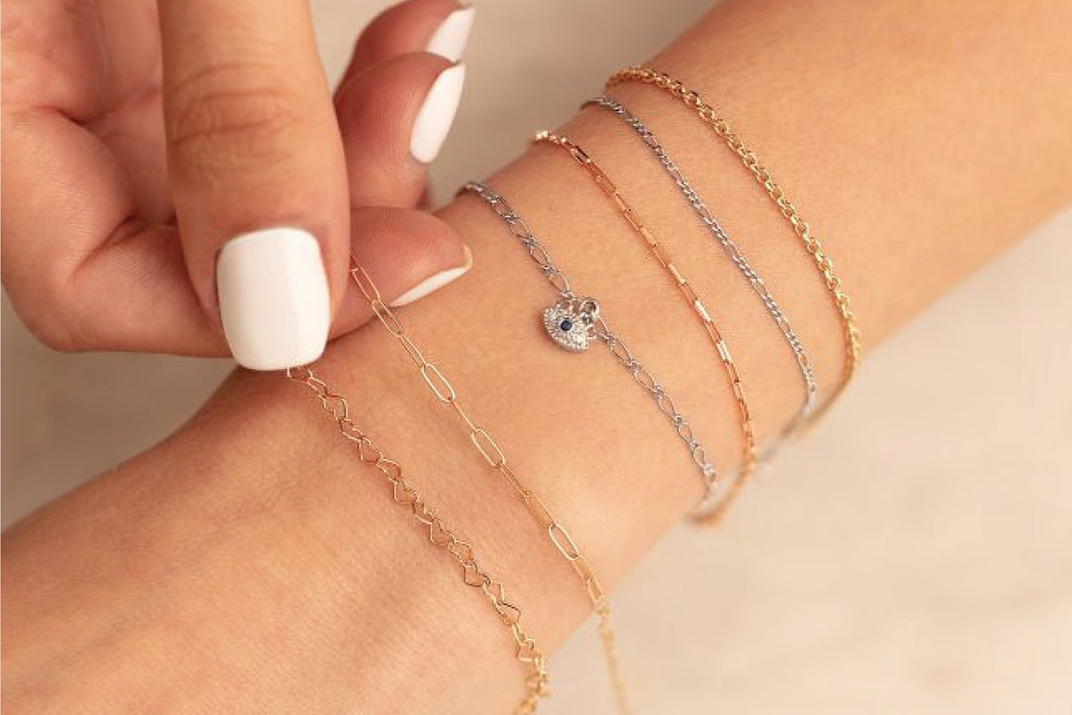 Close-up of a wrist wearing multiple gold bracelets 